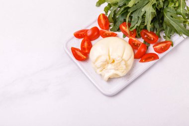 Dilimlenmiş domates ve roka peynirli burrata peyniri.