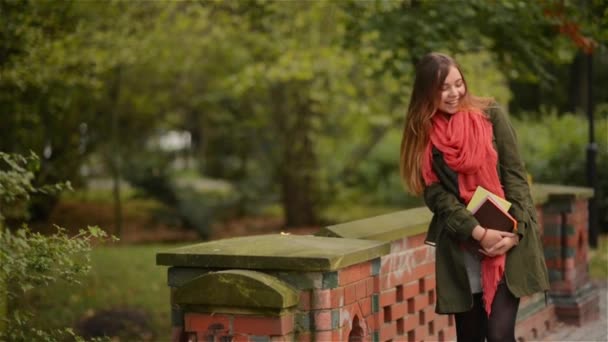 Diák girl gazdaság könyvek fárasztó hátizsák szabadtéri mosolygós boldog séta a parkban. Kaukázusi női főiskolai vagy egyetemi hallgató — Stock videók
