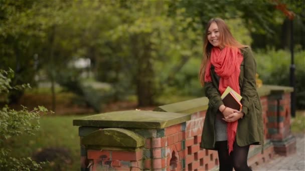 Student tjej håller böcker bär ryggsäck utomhus leende glada promenader i parken. Kaukasiska kvinnlig college eller universitet student — Stockvideo