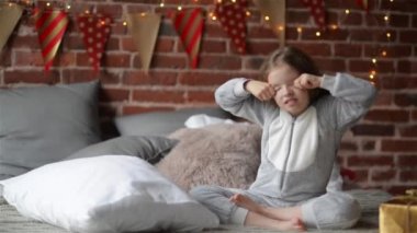Çocuk kız uyan tatil sabah, enjoing şu ile sıcak xmas pijama giymiş onu yatakta mutlu Noeller