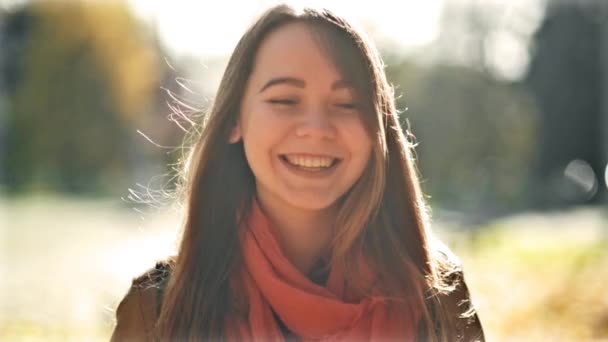 Счастливая молодая женщина, смеясь и глядя в камеру, на фоне осеннего парка. Ранняя осень в октябре . — стоковое видео