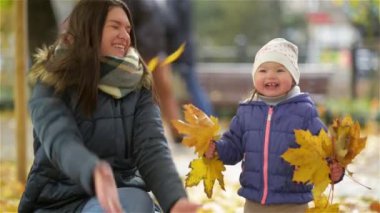 Mutlu genç anne ve onun küçük kızı olan eğlenceli bir sonbahar Park, anne ve kız atma bırakır ve gülme