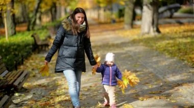 Anne ve kızı parkta elele yürümeye. Sıcak giysiler, Sonbahar sezonu giymiş oldukları.