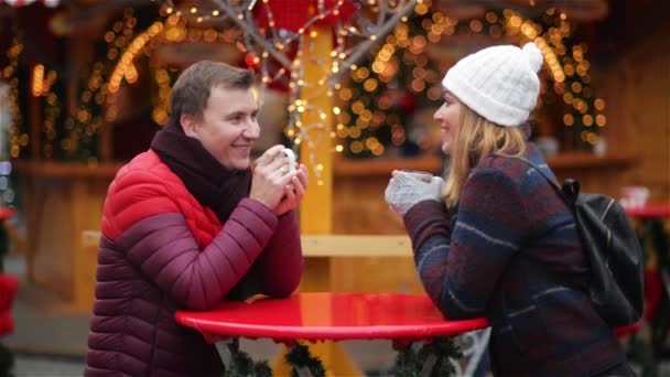 Coppia felice di turisti in abiti caldi bere caffè da tazze nel centro storico, giovane famiglia alla fiera di Natale. Vacanze invernali — Video Stock