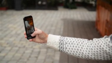Genç bir çekici çift Selfie Smartphone ile alarak bir Noel pazarda görünümünü. Mutlu genç aile sahip eğlenceli Noel Fuarı