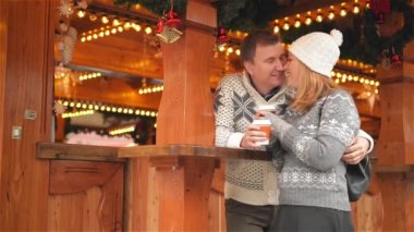 Mutlu genç çift Noel piyasada, Xmas Fuarı kahve içme ve birlikte tüyler ürpertici hoş bir aile eğlenceli ve öpüşme sahip. Mutlu Noeller ve mutlu yeni yıl