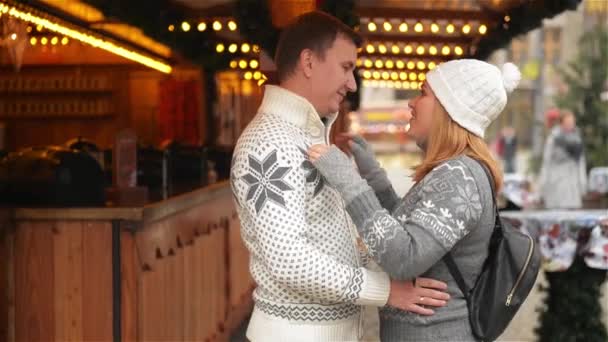 Счастливые пары обнимаются на городской площади, украшенной для Рождественского базара. Девушка обнимает парня на рождественской ярмарке. С Новым годом и Рождеством! — стоковое видео