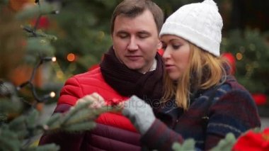 Mutlu çiftimiz Noel ağacı X-mas fuarında seçme. Söz ve Noel Fuarı öpüşme genç ailesi. Mutlu Noeller ve mutlu yeni yıl