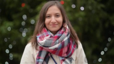 Mutlu kadın portre güneşli bir kış günü, gülen ve kameranın arka plan üzerinde Noel Fuarı bakarak kız açık havada üzerinde. Mutlu Noeller ve mutlu yeni yıl