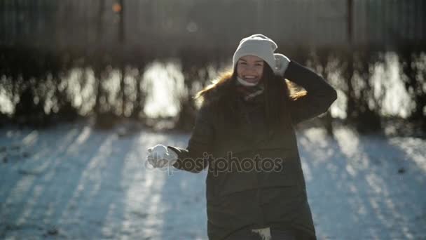 Happy neklidný mladá dívka je házet sníh na fotoaparát má zábava venku v chladné Slunečné ráno. Aktivní žena těší koulovačka mimo. — Stock video