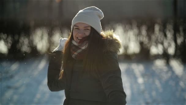 Χαρωπή και δραστήρια γυναίκα είναι ρίψη χιονοστιβάδας στο ύπαιθρο διασκέδαση έχοντας κάμερα κατά τη διάρκεια του χειμώνα. Χαμογελαστό κορίτσι απολαμβάνοντας κρύο ηλιόλουστο πρωί στο πάρκο. — Αρχείο Βίντεο