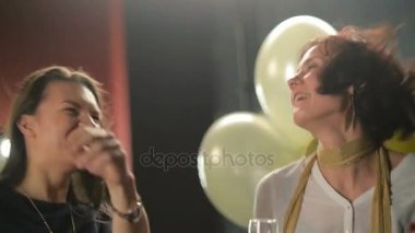 Çekici bayanlar dans ve bir parti sırasında alkol içme vardır. Şampanya ile gözlük diskotek üzerinde tutan iki kadın. Portre, balonlar ve el feneri ile siyah arka plan.