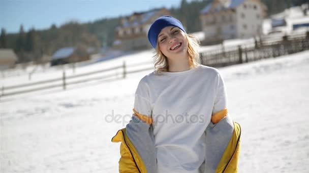 Mulher emocional com cabelo loiro está enlouquecendo se divertindo ao ar livre durante o dia de inverno ensolarado. legal jovem menina no brilhante amarelo jaqueta é rindo e gritando gozando quente tempo fora . — Vídeo de Stock