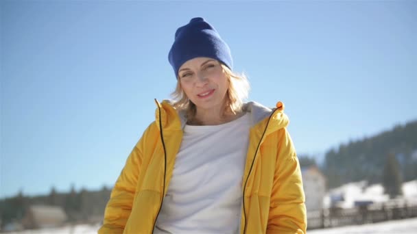 Mujer sonriente está disfrutando del invierno y el paisaje de campo en el fondo del cielo azul. Retrato al aire libre de una joven dama increíble con una sonrisa encantadora . — Vídeos de Stock