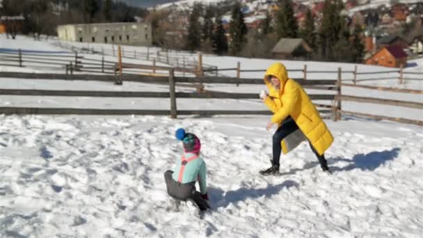 A família ativa está desfrutando de um clima quente ensolarado durante as férias no campo. Mãe inquieta está jogando na luta bola de neve com sua filha e filho no inverno ao ar livre . — Vídeo de Stock