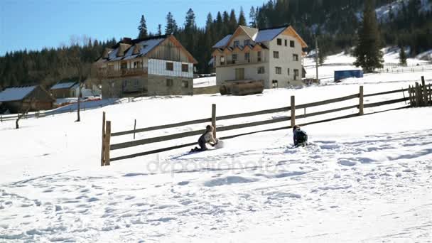 Meisje en jongen zijn een grote sneeuwbal van de heuvel tijdens warme zonnige dag rollen op het platteland in de bergen. Kinderen zijn Winter spel buiten spelen. — Stockvideo