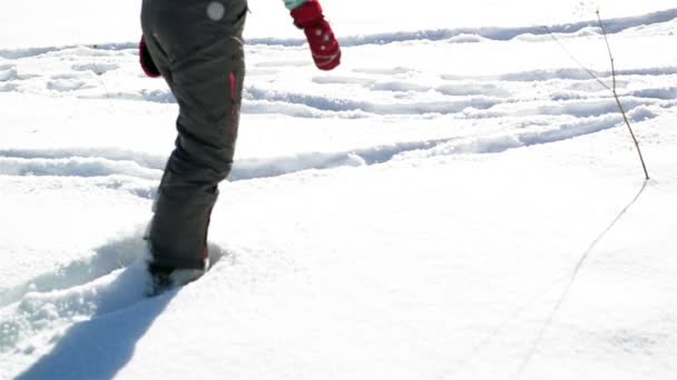 誰かが晴れた冬の日に雪の街を歩くです。影と足跡が地面に. — ストック動画