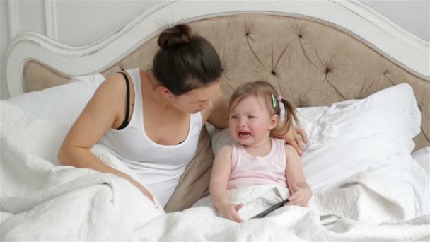 Cute Little Girl z dwóch Ponytails jest płacz siedzi na łóżku. Matka jest próba spokój jej córka w sypialni. — Wideo stockowe