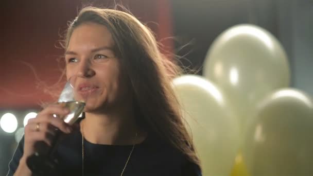 Mujer sonriente con copa de champán en la fiesta. Pretty Lady está bebiendo alcohol. Primer plano retrato de joven morena con el pelo largo aleteo . — Vídeos de Stock