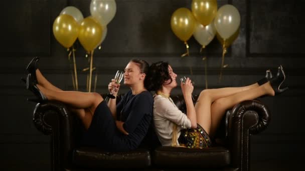 Mulheres felizes estão bebendo álcool durante uma festa. Duas senhoras de salto alto e vestidos curtos são óculos Clinking e rir Desfrute de festa de aniversário . — Vídeo de Stock