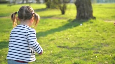 Küçük şirin kız onun annesi tadını güneşli gün açık havada için çalışıyor. Genç kadın ve kızı Hugging ve birlikte parkta oynayan bahar vardır.
