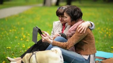 Mutlu aile ile bahar piknik Park sırasında küçük köpek. Her anne ile yetişkin kızı mısın kullanarak Tablet açık havada.
