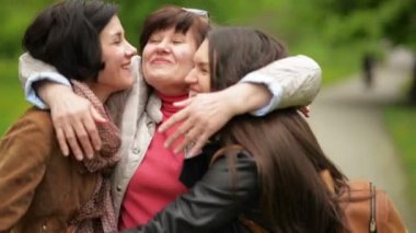 Annesi gülümseyerek sarılma Her iki yetişkin kızları açık havada olduğunu. Üç güzel kadın olduğunu mutlu birlikte.