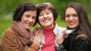İki gülümseyen kız Hugging ve onların anne açık havada öpüşme vardır. Mutlu aile birlikte parkta vakit.