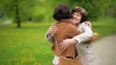 Toplantı yetişkin kızı ve annesi parkta. Her anne sarılma sevgi ve hassasiyet ile çekici esmer olduğunu.