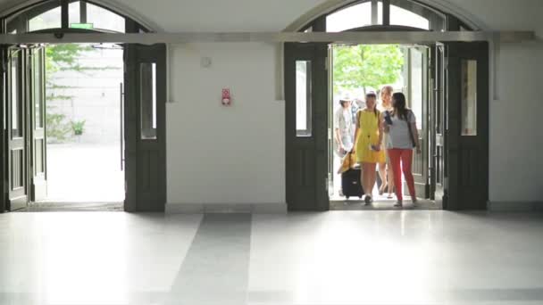 Lindas mujeres jóvenes con equipaje están entrando en el aeropuerto. Happy Girls están rodando sus bolsas de viaje . — Vídeo de stock