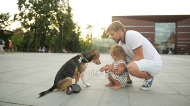 Yakışıklı sakallı babası şehirde günbatımı sırasında kızıyla vakit geçiriyor. Beagle köpek bir pençe için küçük kız verir..