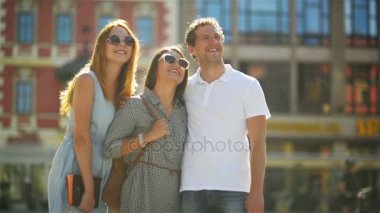 Yakışıklı adam beyaz gömlek giymiş iki kızla çok güzel moda güneş gözlüğü ve elbiseler eski şehir Meydanı'nda duruyor.