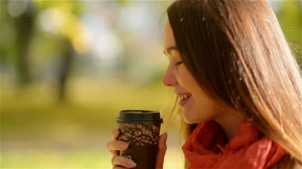 Осенняя девушка пьет кофе. Осенняя концепция молодой женщины, наслаждающейся горячим напитком из одноразового чашки кофе в Осеннем парке — стоковое видео