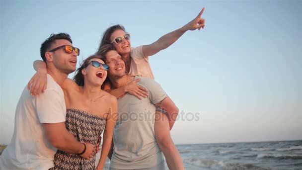 웃 고는 저녁에 바람이 부는 날씨 동안 해변에 웃 고 여자 친구와 두 잘생긴 강한 남자. — 비디오