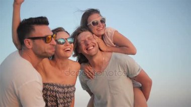 Dört mutlu gülümseyen kadın ve erkek gün batımını birlikte onların tatil yaz saati sırasında deniz keyfi.