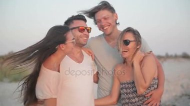 Akşam plajda. Eğleniyor birlikte rüzgarlı havalarda deniz ve güneşin tadını dört arkadaş portresi.