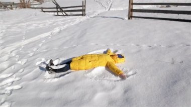 Neşeli kadın kış oyun oynuyor. Bringh sarı ceket Lying zemin ve yapım kar melek sahip eğlenceli sırasında bir gün dışarıda kızdır. Tatil kavramı.