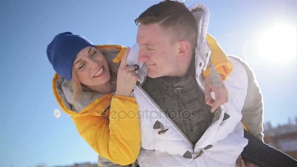 Όμορφη ξανθιά γυναίκα είναι αγκάλιασμα όμορφος άνδρας κάθεται για του ώμους κατά τη διάρκεια της χειμερινές διακοπές στα βουνά. Closeup πορτρέτο του άνδρα και της γυναίκας στην αγάπη. — Αρχείο Βίντεο