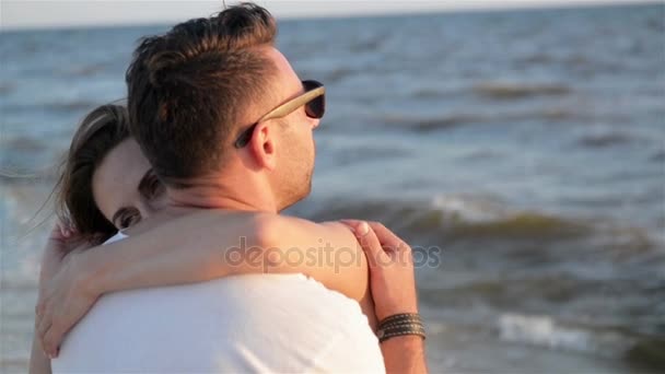 Vista trasera de la joven pareja enamorada abrazándose cerca del mar en el fondo de las olas . — Vídeos de Stock