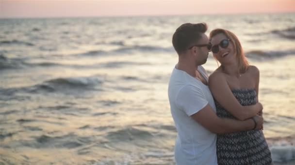 Hansome fidanzato abbraccio suo bionda fidanzata standing vicino il mare durante tramonto . — Video Stock