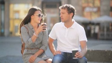 Mutlu çift güneşli yaz gün boyunca şehir meydanında bankta oturmuş kahve içme.