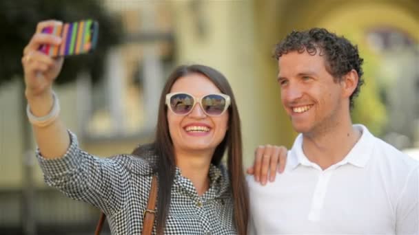 Menina atraente em óculos de sol na moda tomando selfie em pé ao ar livre na cidade com seu namorado durante o dia de verão ensolarado . — Vídeo de Stock