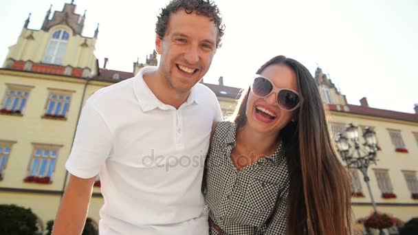 Pareja alegre con sonrisas encantadoras posando al aire libre mirando a la cámara durante el soleado y cálido día de verano . — Vídeos de Stock