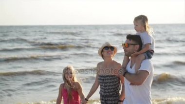 Birlikte yaz tatili deniz Beach çevresinde yürüyüş mutlu bir aile portresi. Güçlü baba kızlarından biri onun omuzlarında Holding.