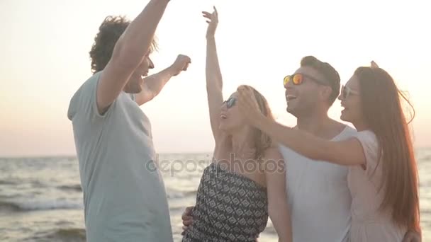 웃 고 바람이 부는 날씨 동안 해변에 포옹 놀라운 여자 친구와 두 남자의 초상화. — 비디오
