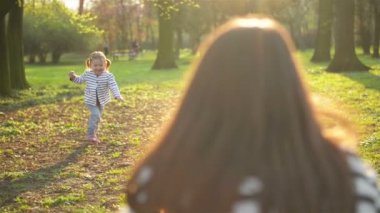 Küçük kız anne harcama ücretsiz zaman birlikte açık havada ile güneşli hava zevk olduğunu. Çalışan anne ve onu Park boyunca baharda kucaklayan güzel kızıdır.