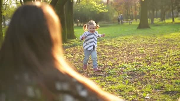 Pretty Daughter está correndo para a mãe e abraçá-la no parque durante a primavera. Engraçado menina está desfrutando do tempo ensolarado com a mãe passar tempo livre juntos ao ar livre . — Vídeo de Stock
