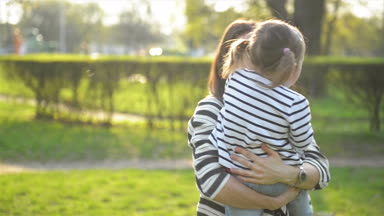 Taşıyan küçük şirin kız el ve onu döne döne üzerinde güneş gözlüğü ile oldukça esmer. Mutlu anne ve kızı bahar Park açık havada portresi.
