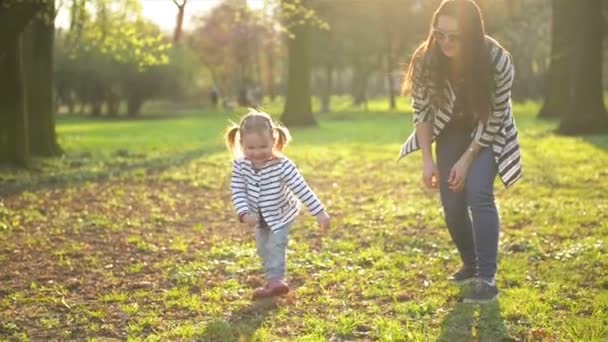 Aktiva kvinnliga barn ha roligt under solig vårdag. Rolig liten flicka är kör bort från hennes mor spela utomhus i parken. — Stockvideo