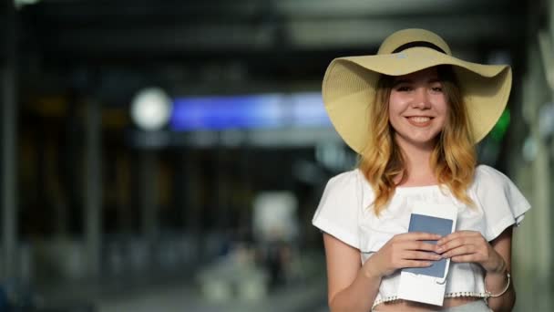 Hübsches Mädchen mit Sommermütze wartet am Flughafen auf ein Flugzeug, das ihren Reisepass und ihr Ticket in der Hand hält. Reisekonzept. — Stockvideo